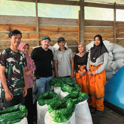 A group of people standing around hessian bags full of coffee