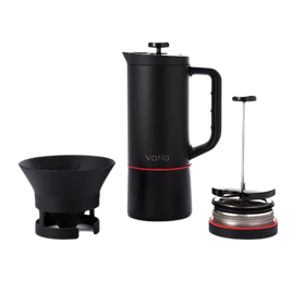 A black Varia coffee brewer with additional accessories including a paper filter, a brewing guide, and a user manual.